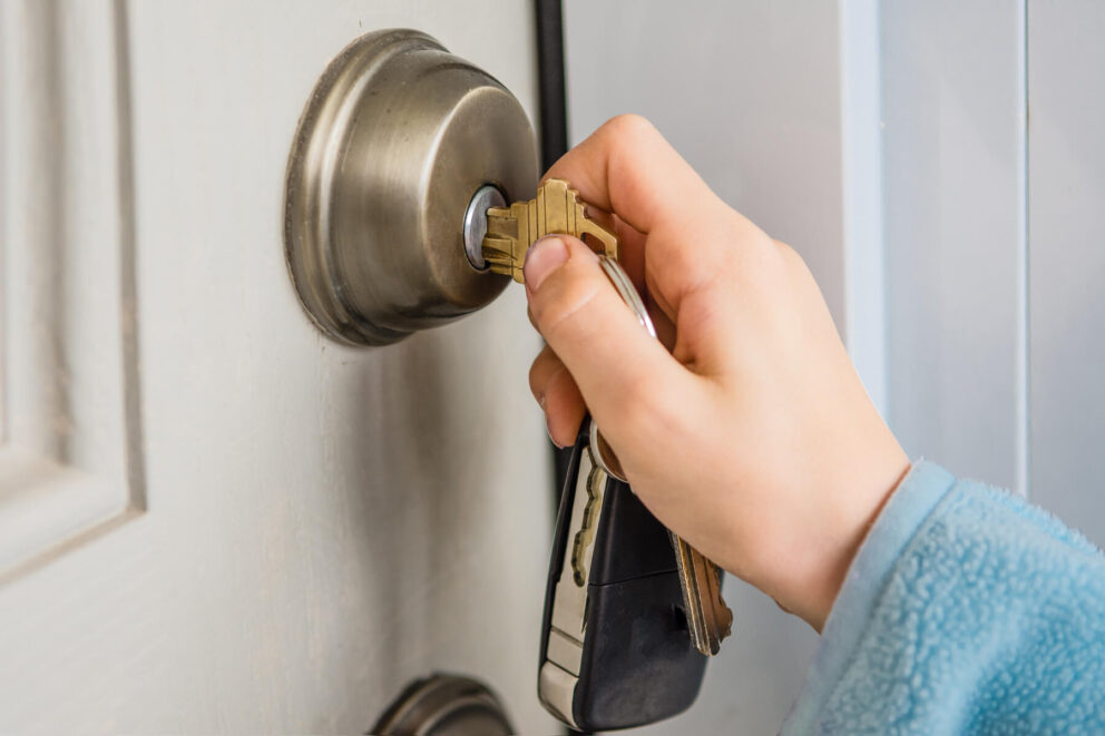 A hand putting the front door key in a door lock
